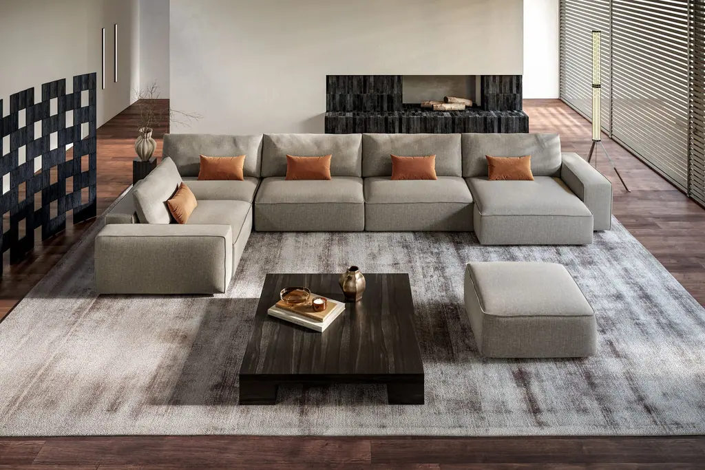 Divano componibile grigio con cuscini arancio in un soggiorno, LeComfort